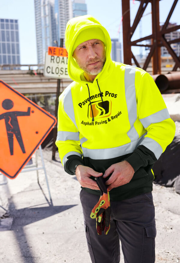 Working man in bright yellow safety gear hoodie. He has gloves in is hand. He is looking to the right