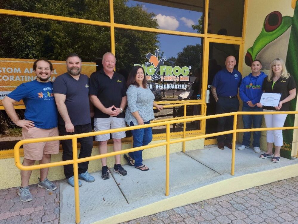 Tina Bacon-Defrece, Bill Currie, and Big Frog Employees stand in front of Big Frog Headquarters