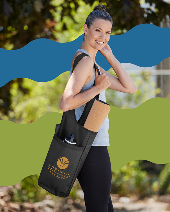 Smiling woman carrying a branded yoga mat bag and drinkware by Big Frog